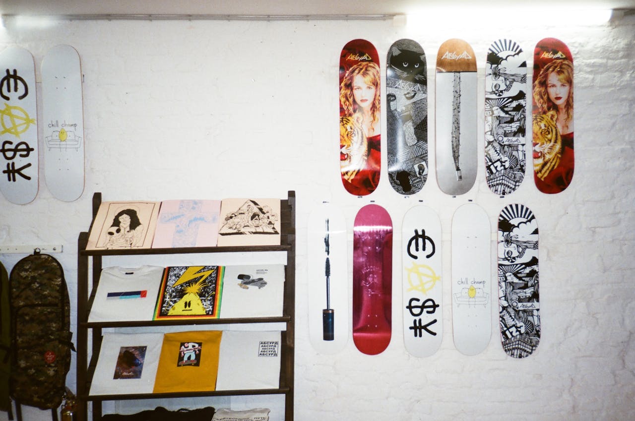 A collection of artistic skateboards and prints displayed on a white brick wall, showcasing modern art and design.