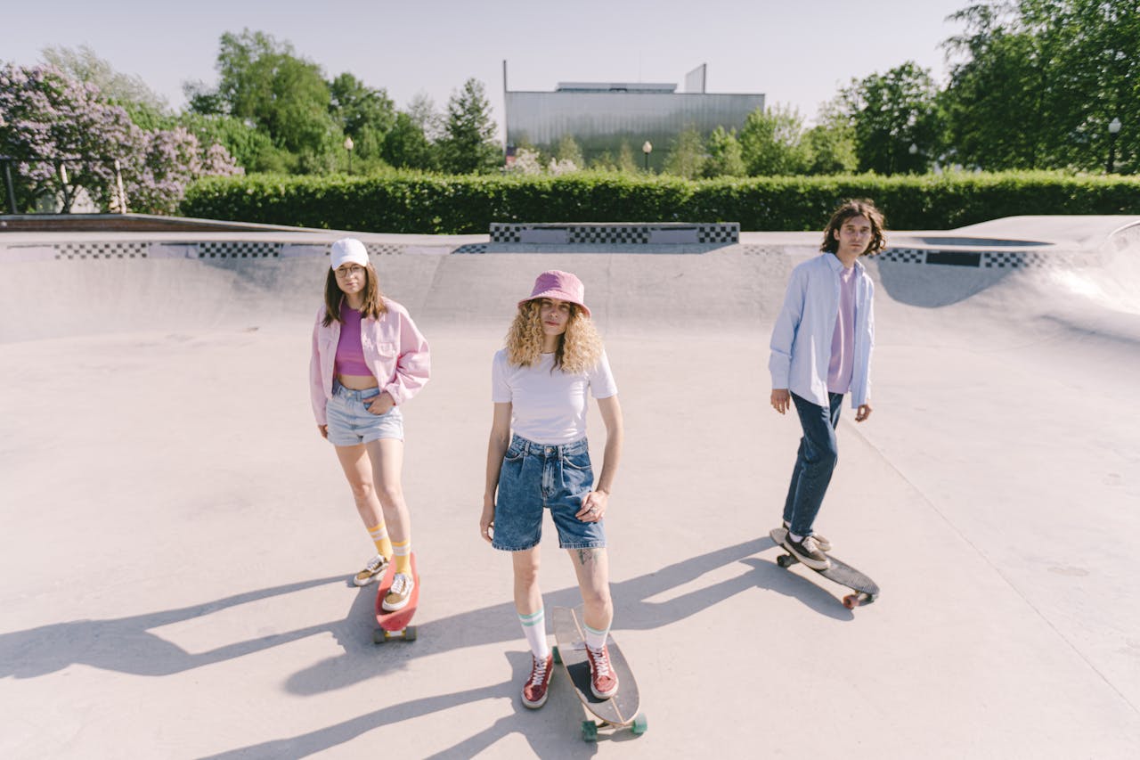 Three young adults skateboarding in an outdoor skate park on a sunny day.